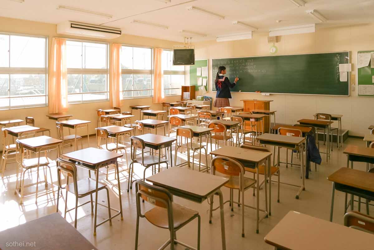 教室の黒板に書く女子高生