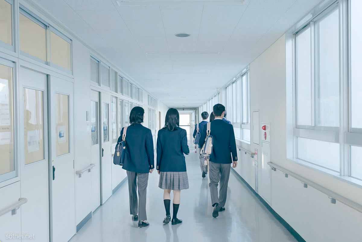 廊下を歩く高校生たちの後ろ姿
