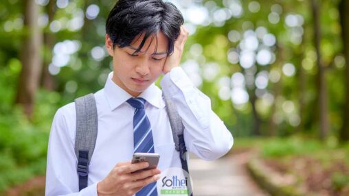 スマホを見て悩む男子高生